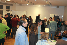 Das Bild zeigt Menschen, die in Arbeitsgruppen an Tischen diskutieren.