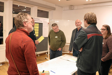 Das Bild zeigt Menschen, die an einem Tisch mit einer Karte stehen und diskutieren.