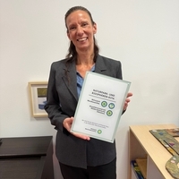 Die Kita-Leiterin Natascha Barz-Griese hält die Plakette zur Auszeichnung als Naturpark- und Biosphären-Kita hoch.